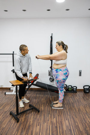 Nutritionist measuring weight of overweight woman in gymの写真素材