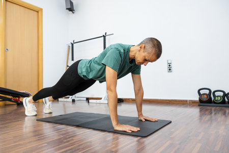 Determined sportswoman performing plank exercise for core strengthening in gymの写真素材