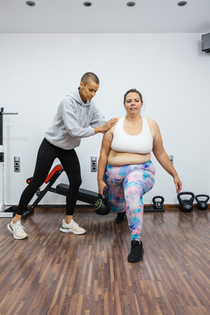 Personal trainer supporting overweight client during kettlebell workoutの写真素材