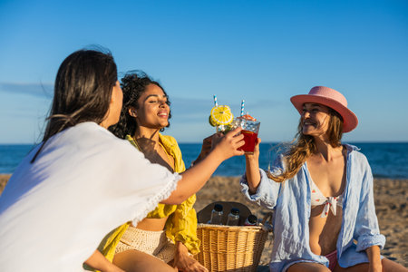 Multiethnic women toasting cocktails at beach picnicの写真素材