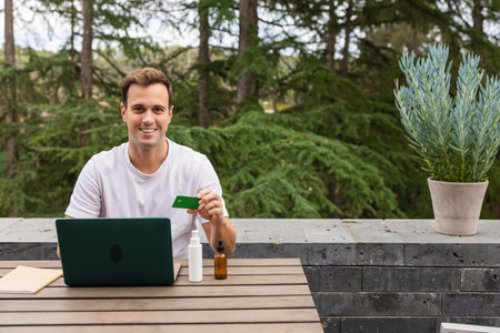 Man buying online body products with credit card on a terrace
