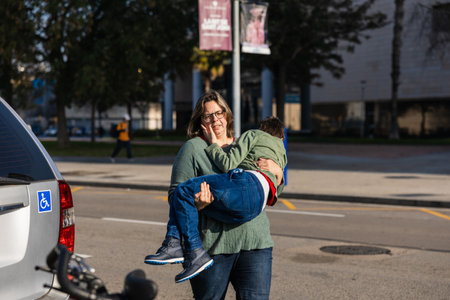 Mother carrying disabled child to wheelchair accessible vehicleの写真素材