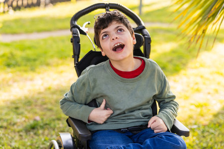 child with disability enjoying a sunny day in wheelchair at parkの写真素材