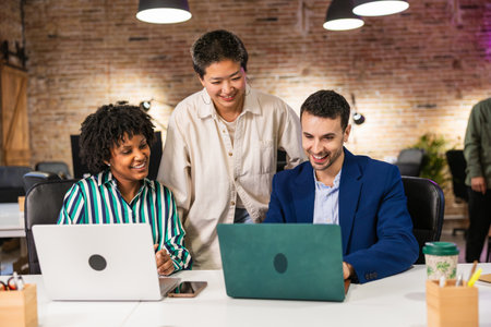 Multi ethnic team collaborating on laptops in modern officeの写真素材