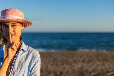 Tourist making silence gesture on the beach at sunsetの写真素材