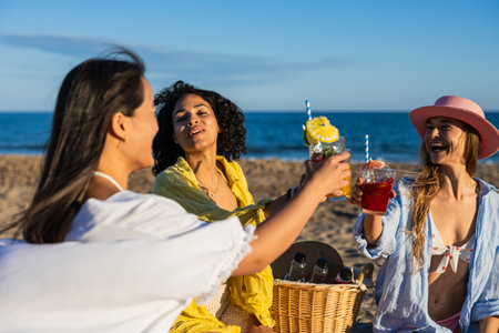 Multiethnic friends toasting cocktails at beach picnic enjoying summer vacationの写真素材