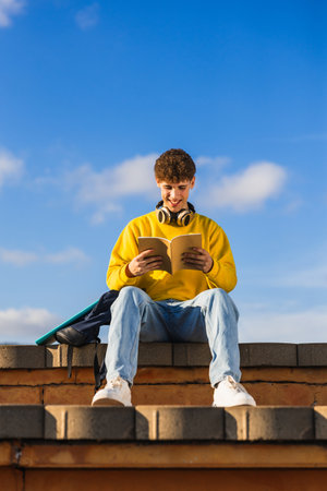 Smiling student reading book outdoors on sunny dayの写真素材