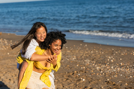 Happy multi ethnic friends piggybacking on the beachの写真素材