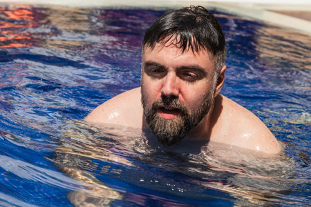 Bearded man relaxing and enjoying swimming pool on summer vacationの写真素材