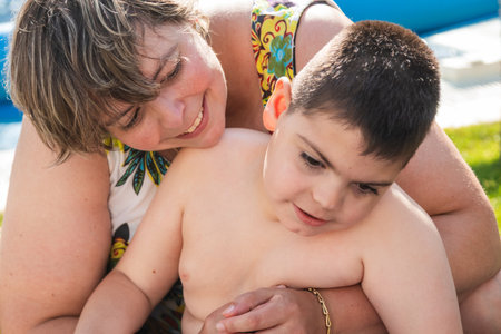 Caring mother supporting child with disability in poolの写真素材