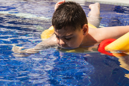 Child with cerebral palsy swimming with floatation device in poolの写真素材