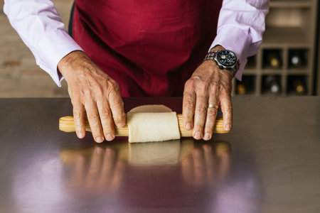 Chef rolling dough with rolling pin in kitchenの写真素材