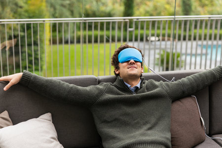 Man relaxing on sofa wearing temperature controlled sleep mask