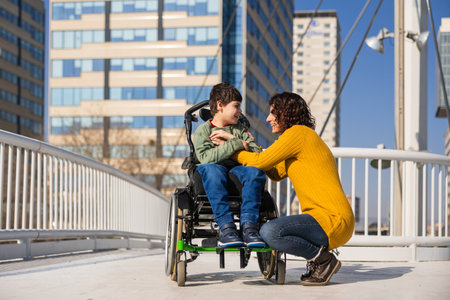 Mother comforting her son with disability in a wheelchair in the cityの写真素材