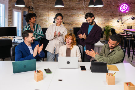 Team congratulating project manager clapping in modern officeの写真素材
