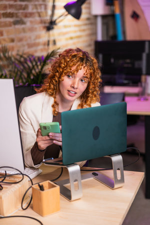 Freelancer working at her desk using laptop and smartphoneの写真素材