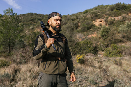 Hunter carrying rifle looking for animals in the distanceの写真素材