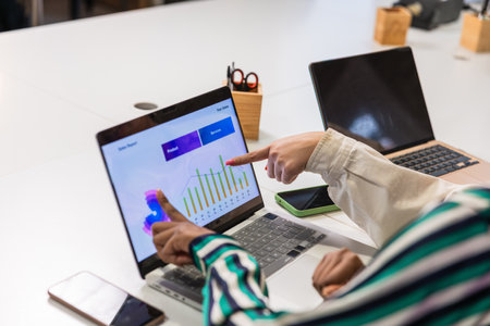 Businesswomen pointing at charts on laptop screen during a meeting
