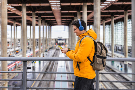 Young traveler using smartphone and listening music in train stationの写真素材