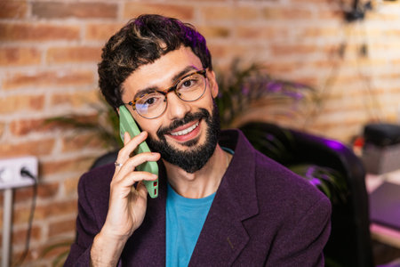 Young caucasian entrepreneur smiling and talking on phone in office