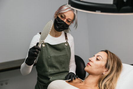 Satisfied client checking eyebrows after microblading procedureの写真素材