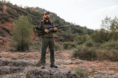 Hunter standing on rock holding rifle in forest