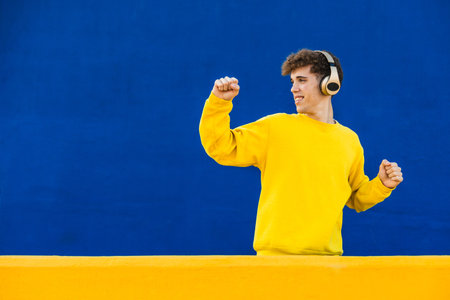 Young student listening to music with headphones and dancingの写真素材