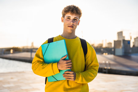 Young college student holding binder and wearing backpack near campusの写真素材