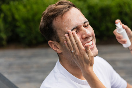 Woman applying sunscreen lotion to mans face for sun protection