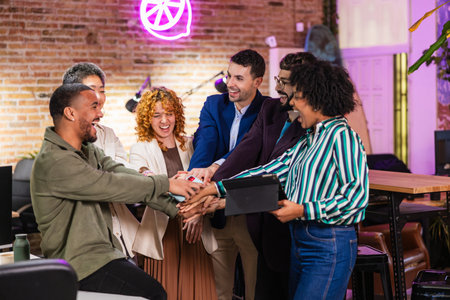 Startup team celebrating success, joining hands in modern office