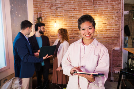 Young asian manager using digital tablet with coworkers collaborating in the backgroundの写真素材