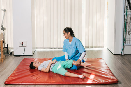 Physiotherapist assisting child with cerebral palsy during floor exercisesの写真素材