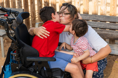 Mother kissing and hugging her children with cerebral palsy
