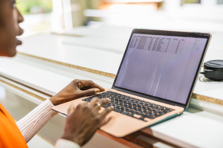 Worker managing lumberyard inventory on laptop computer