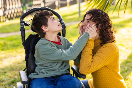 child playing with mother outdoors in wheelchair, cerebral palsy and intellectual disability awarenessの写真素材