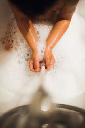 Boy washing his hands during his bathtimeの写真素材