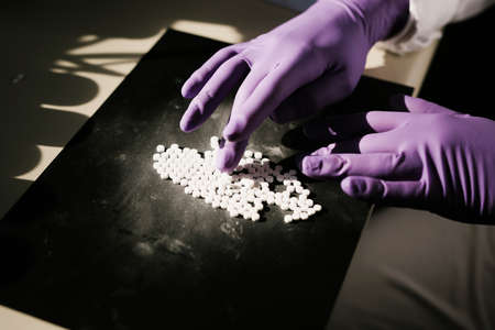Hands of a scientist working with some pillsの写真素材
