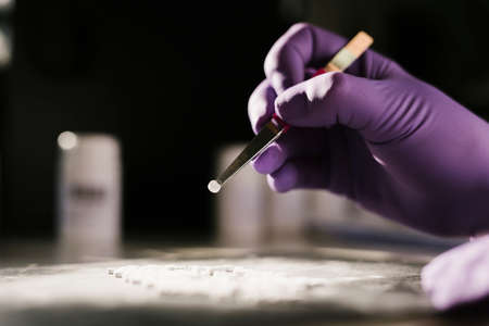 Hands of a scientist working with some pills