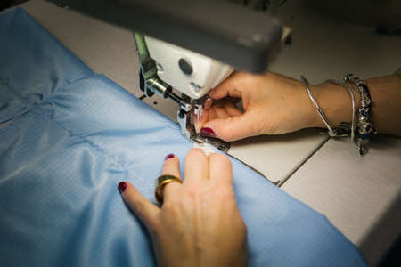 Hands of a seamstress sewing medical clothes with a sewing machineのeditorial素材