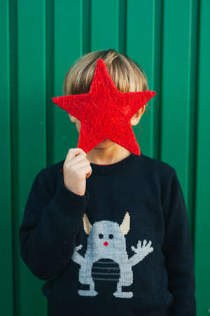 6 years old boy holding a red star infront of his faceの写真素材
