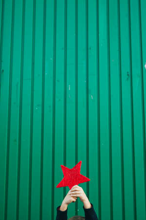 6 years old boy holding a red star against a green backgroundの写真素材