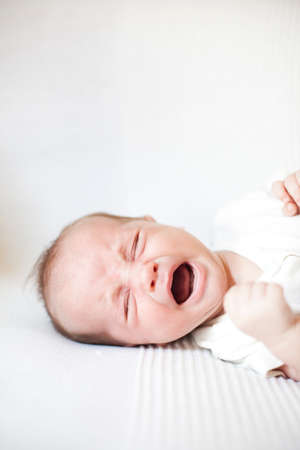 Newborn boy desperately crying on a sofaの写真素材