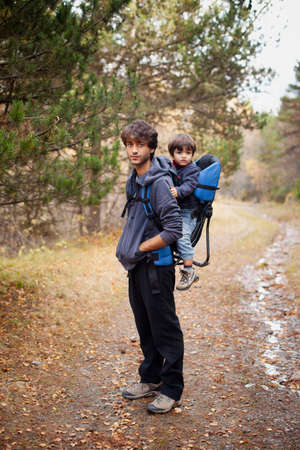 Man carrying a two year old boy on his back during an excursion on the mountainの写真素材