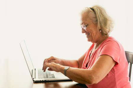 Senior woman using laptop and having an on-line conversationの写真素材