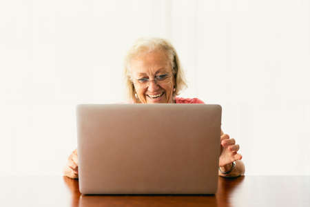 Senior woman using laptop and having an on-line conversationの写真素材