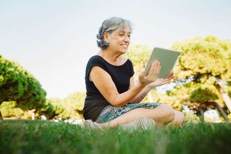 Senior woman chatting on-line with his tablet in a park