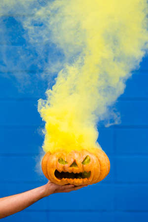 Spooky pumpkin With yellow Smoke against a blue background