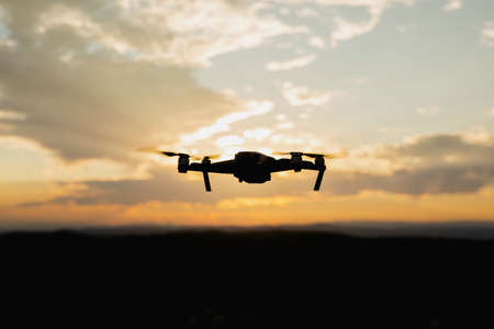 Silhouette of a drone flying at Sunsetの写真素材