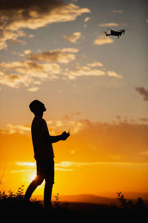 Silhouette of a young man operating a drone in A Rural Setting on sunsetの写真素材