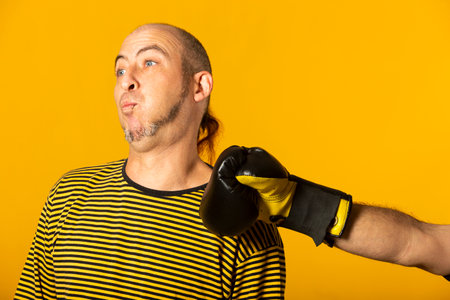 Middle aged man getting punched in the jaw on yellowの写真素材